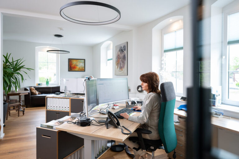 Mitarbeitern an ihrem Schreibtisch im großzügigen, modernen Büro der Prisma Finanzkonzept GmbH